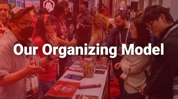 Photo of CWA members having organizing conversations at a conference with the title "Our Organizing Model".